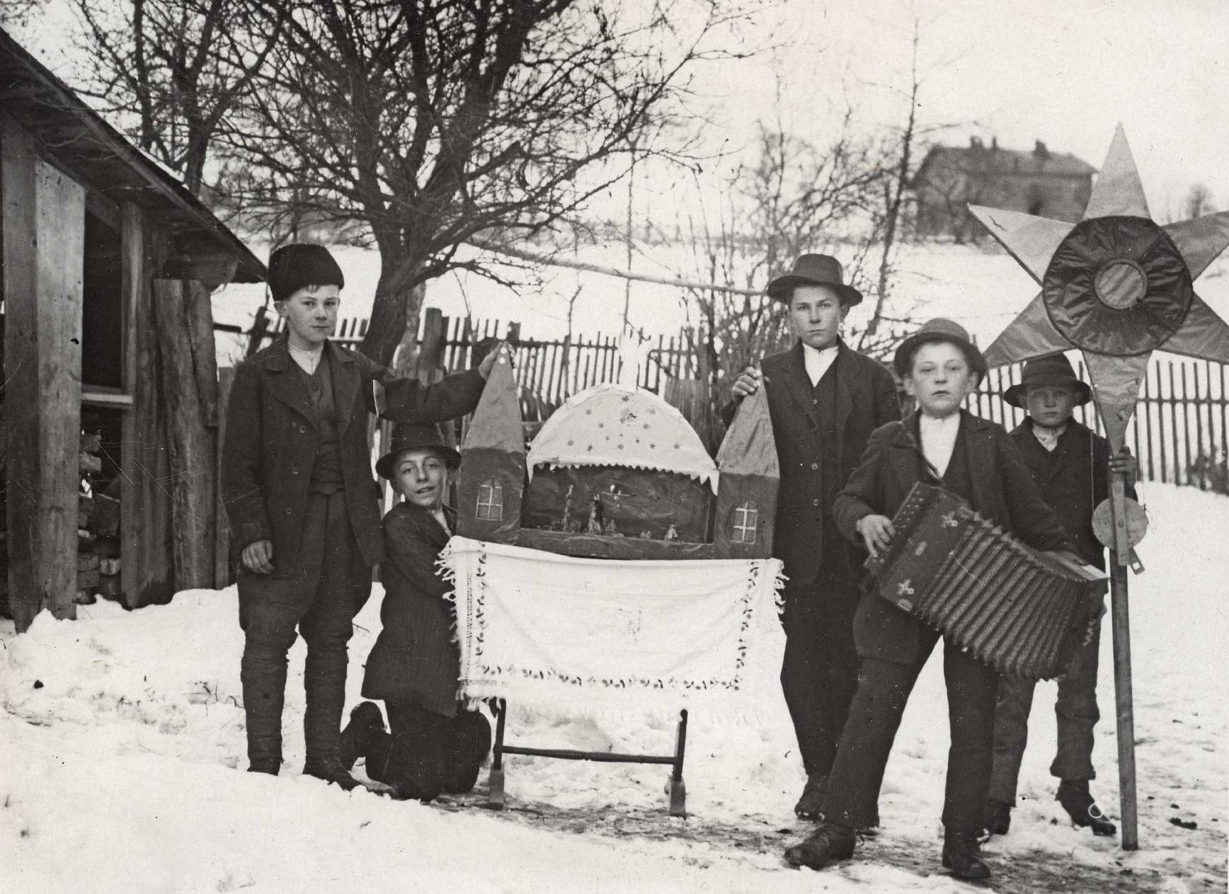 Czarnobiałe zdjęcie, na nim grupa młodych chłopców prezentująca szopkę
