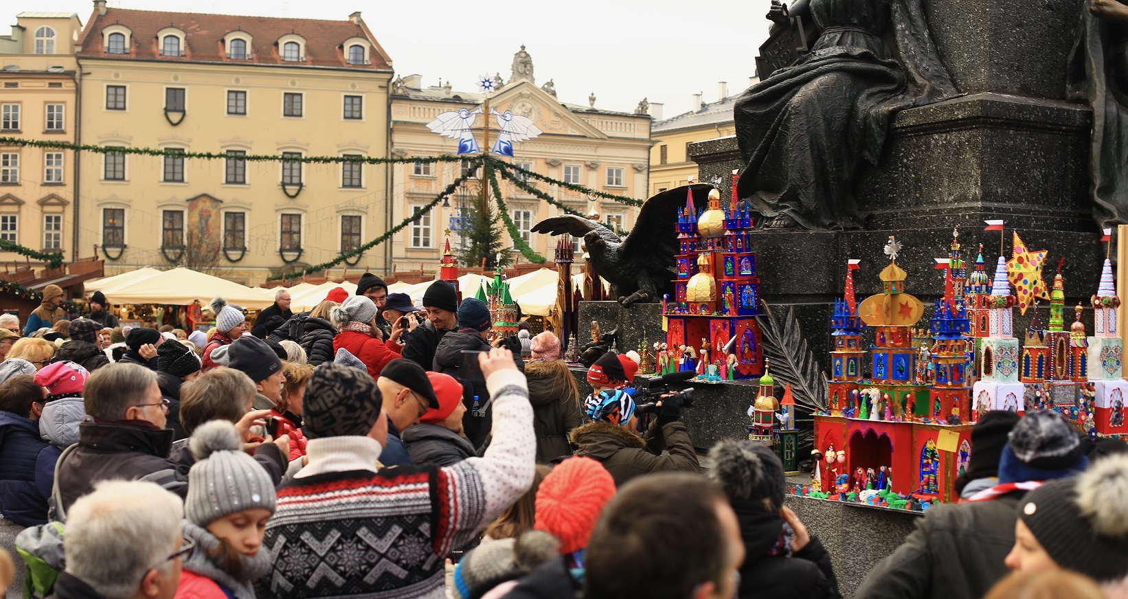 tłum ludzi przygląda się i fotografuje szopki ustawione pod pomnikiem Adama Mickiewicza w Krakowie