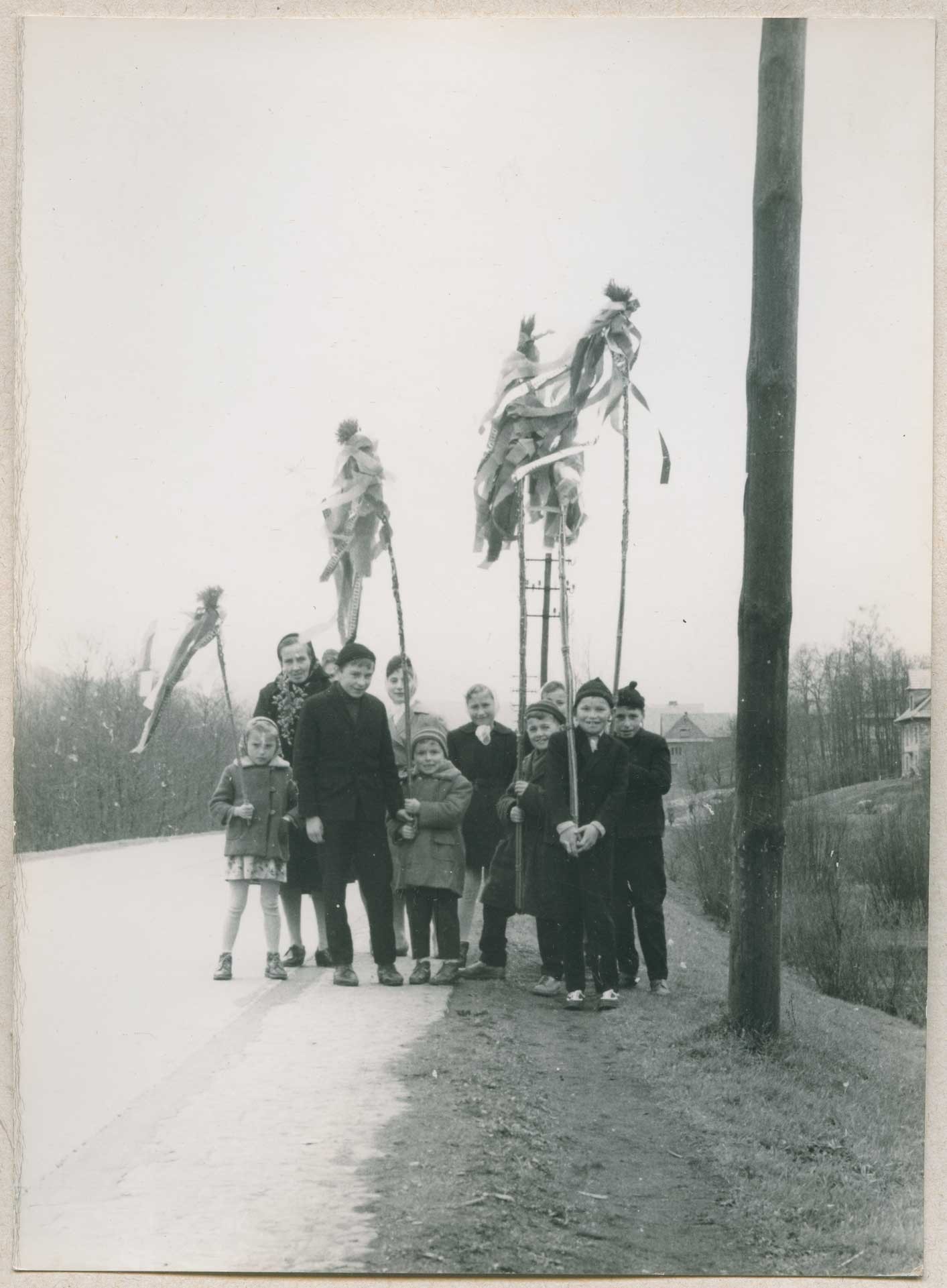 czarnobiałe zdjęcie, grupka dzieci z wysokimi palmami pozuje do zdjęcia przy drodze